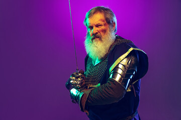 Portrait of senior greybearded man, brave and brutal medieval warrior or knight in armor with sword...