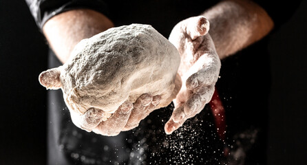 flying pizza dough with flour scattering in a freeze motion of a cloud of flour midair on black....