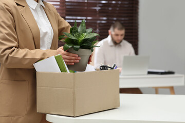 Dismissed woman packing personal stuff into box in office, closeup