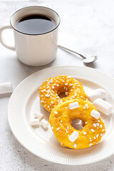 Two donuts with marshmallows and a cup of tea or coffee