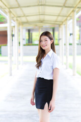 Portrait of an adult Thai student in university student uniform. Asian beautiful young girl standing smiling happily at university