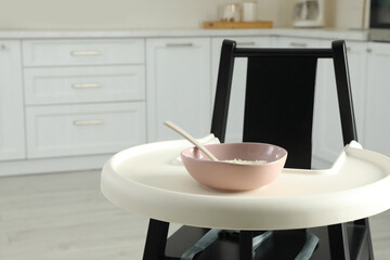 Baby high chair with healthy food in kitchen. Space for text