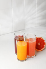 Three Freshly squeezed juices in glass on white table. Red orange, grapefruit, pomegranate juice for menu. Mock up