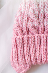 Pink knitted beanie on a white background