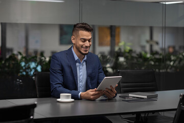 Fototapeta na wymiar Smiling handsome middle eastern entrepreneur using digital tablet