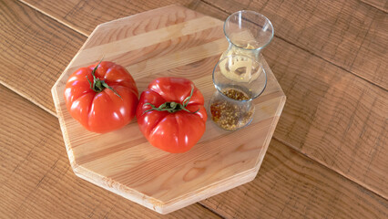 Cutting wooden board with whole red tomatoes and bowls with sauces. Organic vegetarian food.