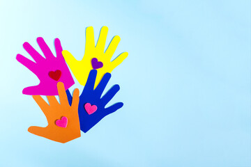 Abstract background colored paper depicting children's hands with colored hearts on a light background.