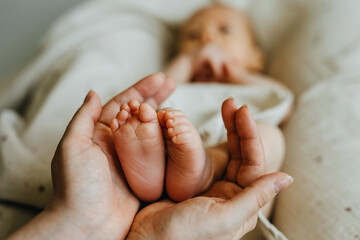 Closeup of mothers hands holding little newborn baby feet.
