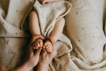 Closeup of mothers hands holding little newborn baby feet.