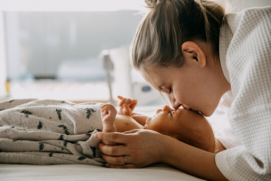 Mother kissing one month old baby on forehead, at home.