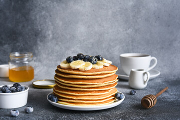 Homemade pancakes with syrup and berries. Morning and breakfast: pancakes with banana and blueberries.