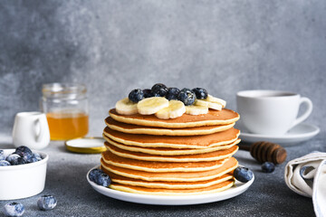 Homemade pancakes with syrup and berries. Morning and breakfast: pancakes with banana and blueberries.