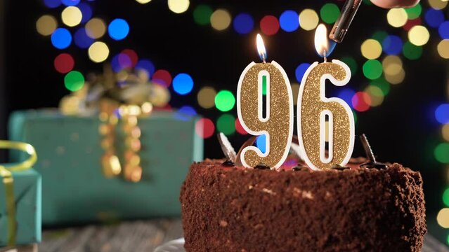 Number ninety-six birthday candle on a sweet cake on the table, 96th birthday. Fire from the lighter, blow out the holiday candle.