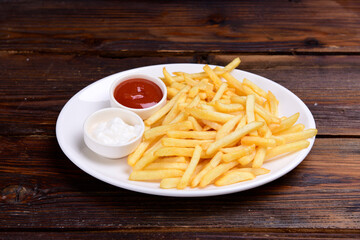 French fries on a plate with tomato sauce and mayonnaise