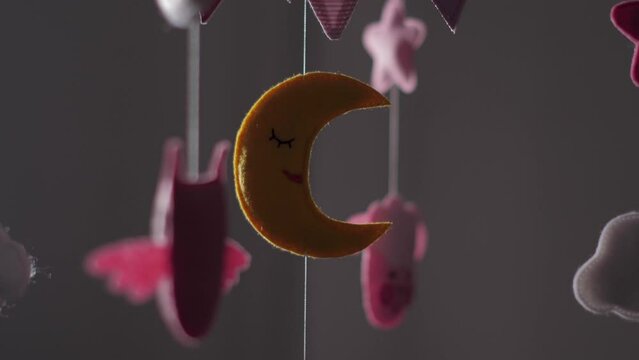 baby mobile with blue hand-stitched animal and bird toys with yellow moon on white wall background. spinning on the baby's crib in the room