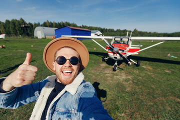 Selfie photo happy tourist man pilot in hat and glasses background white aircraft cockpit. Concept...