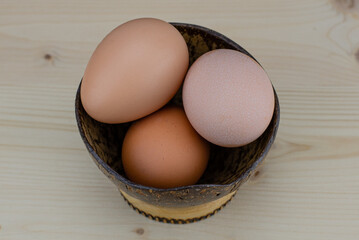 Cooking eggs in a coconut bowl. Protein ingredient for a healthy breakfast. Omelet preparation. Broken eggshells on the table. The transparent, yellow contents of the raw eggs. 