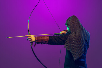 Studio shot of young bearded man in image of medieval warrior, archery in chain armor isolated over...