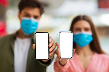 Couple Showing Smartphones Empty Screens Wearing Protective Face Masks Indoors