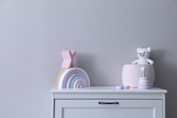 Child's toys on chest of drawers near light grey wall indoors
