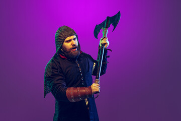 Studio shot of young bearded man in image of medieval warrior, archery in chain armor with ax...