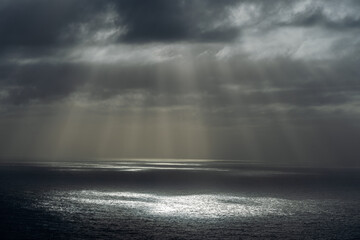 Rays of sun through dark clouds at ocean.
