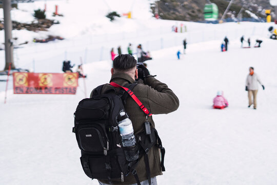 person with backpack in the snow taking pictures