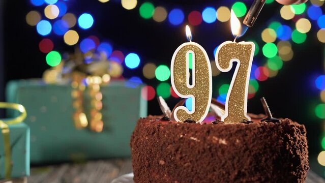 Number ninety-seven birthday candle on a sweet cake on the table, 97th birthday. Fire from the lighter, blow out the holiday candle.