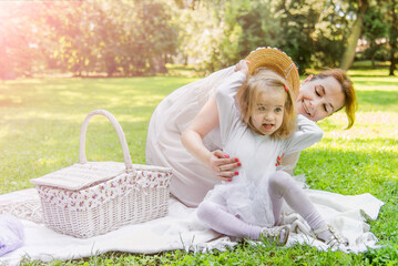 Beautiful little girl in a park on a picnic with straw basket and hat. Spring sunny concept. Happy mothers day. Happy loving family. Mother and daughter.