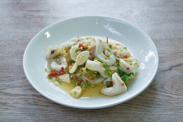 Thai spicy and sour steamed slice squid salad in lemon sauce on plate