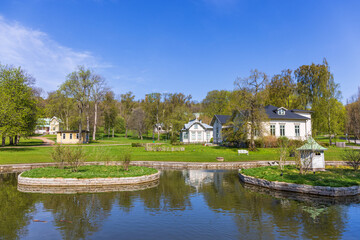 Fototapeta na wymiar Parkland with a pond and old wooden houses