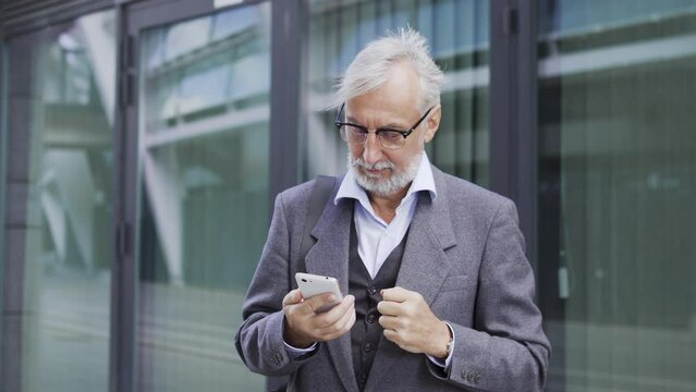 Successful bearded man office worker making yes gesture, playing on stock exchange, buying and selling shares, increasing their value in online app on smartphone