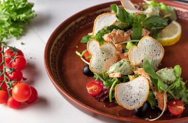 Warm salad with grilled salmon, cherry tomatoes and white bread croutons, close-up