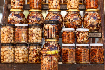 Nuts and honey. Walnuts, hazelnuts, almonds in honey Jars. Variety of honey on shelves