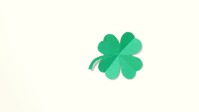 St. Patrick's Day. A leaf of clover cut out of paper is spinning on a white background. High quality 4k footage. vertical video