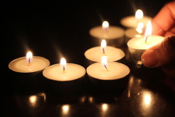 Man's hand lighting several candles on a wooden table