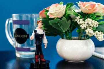 Composition of a vase of flowers, a male figurine and a glass mug