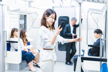 Fototapeta premium 電車でスマホを使う若い女性