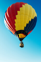 Multicolored hot air balloon on blue sky close up vertical