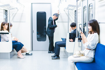 電車でスマホを使う若い女性