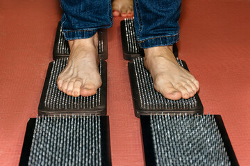 Bare feet on a path made of Sadhu boards on a red background