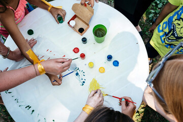 People paint with paints on a white table in nature