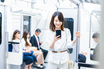 電車でスマホを使う若い女性