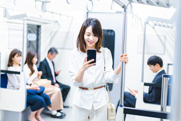 電車でスマホを使う若い女性