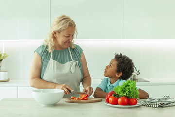 Cute mature woman and her son preparing healthy food together standing at a worktop in the kitchen