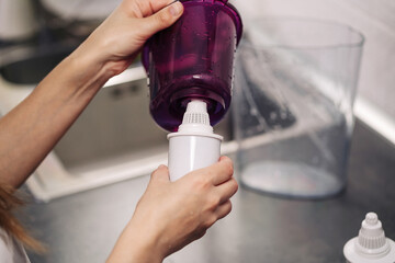 Woman replacing filter in a water pitcher. Female hand removes an old tap water purification...