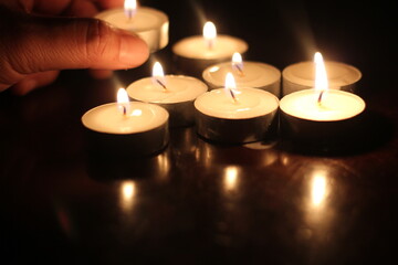 Man's hand lighting several candles on a wooden table