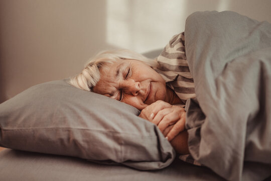 Beautiful 50s woman sleeping in bed at night. People, relax and comfort
