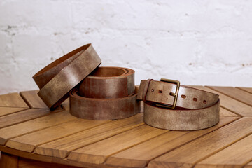 Fototapeta premium Brown genuine leather straps on a wooden table