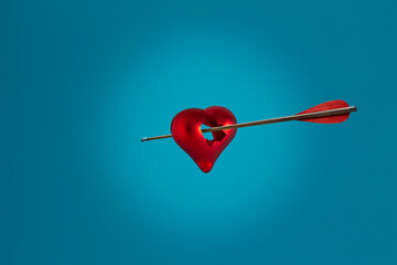 Creative love concept with broken red heart. Minimal idea of the heart and arrow on blue background.